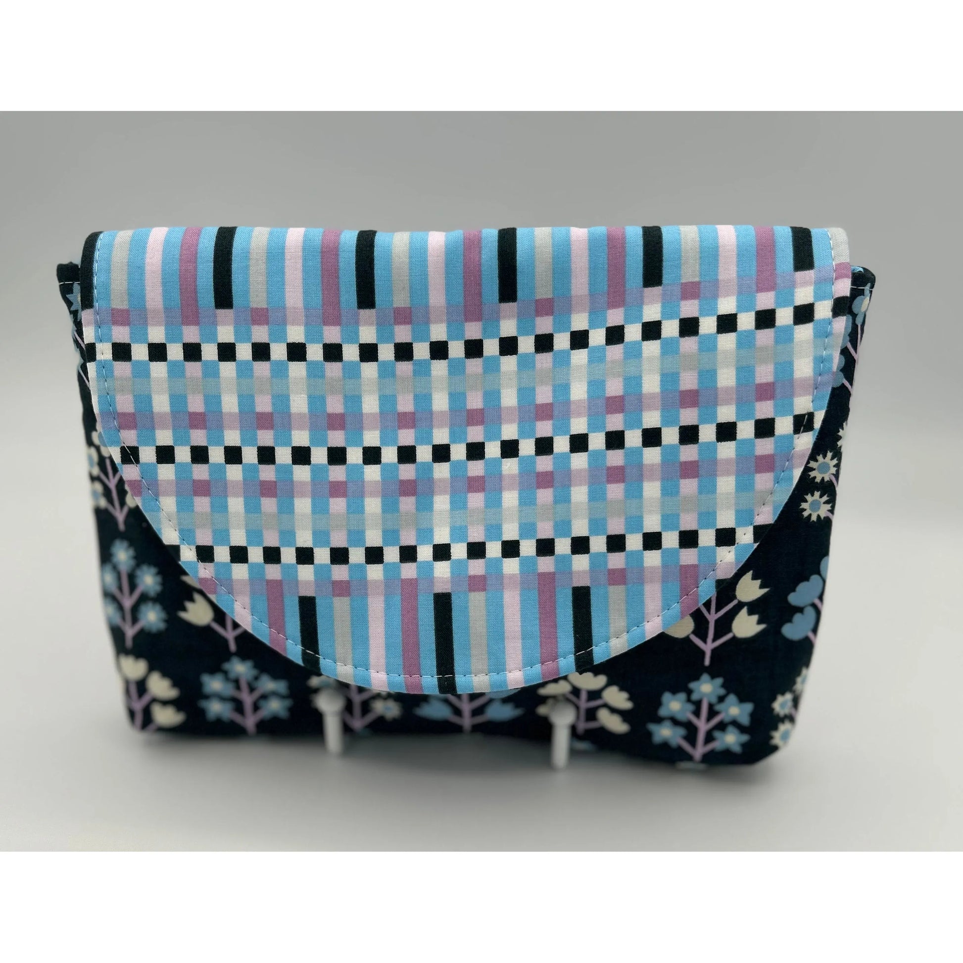 Fabric pouch with checkered pattern and floral accents on a gray background