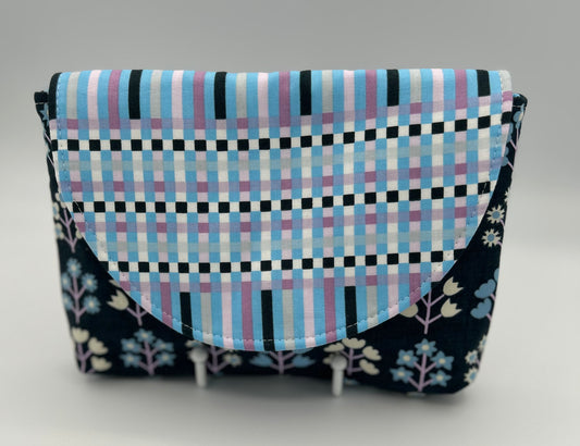 Fabric pouch with checkered pattern and floral accents on a gray background